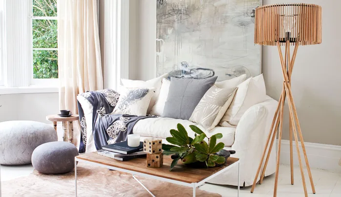 Cozy living room with a white sofa, colorful pillows, a wooden coffee table, and a modern floor lamp.