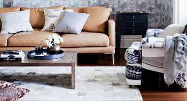 Cozy living room with a tan leather sofa, patterned armchair, coffee table, and decorative pillows.