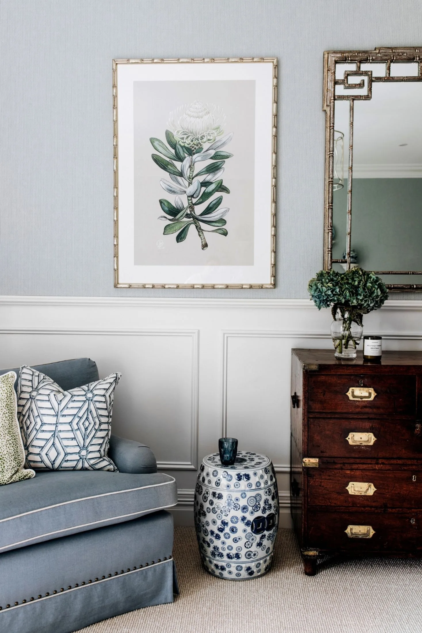 Bedroom nook with blue sofa, dynasty stool, antique dresser and wainscoting.