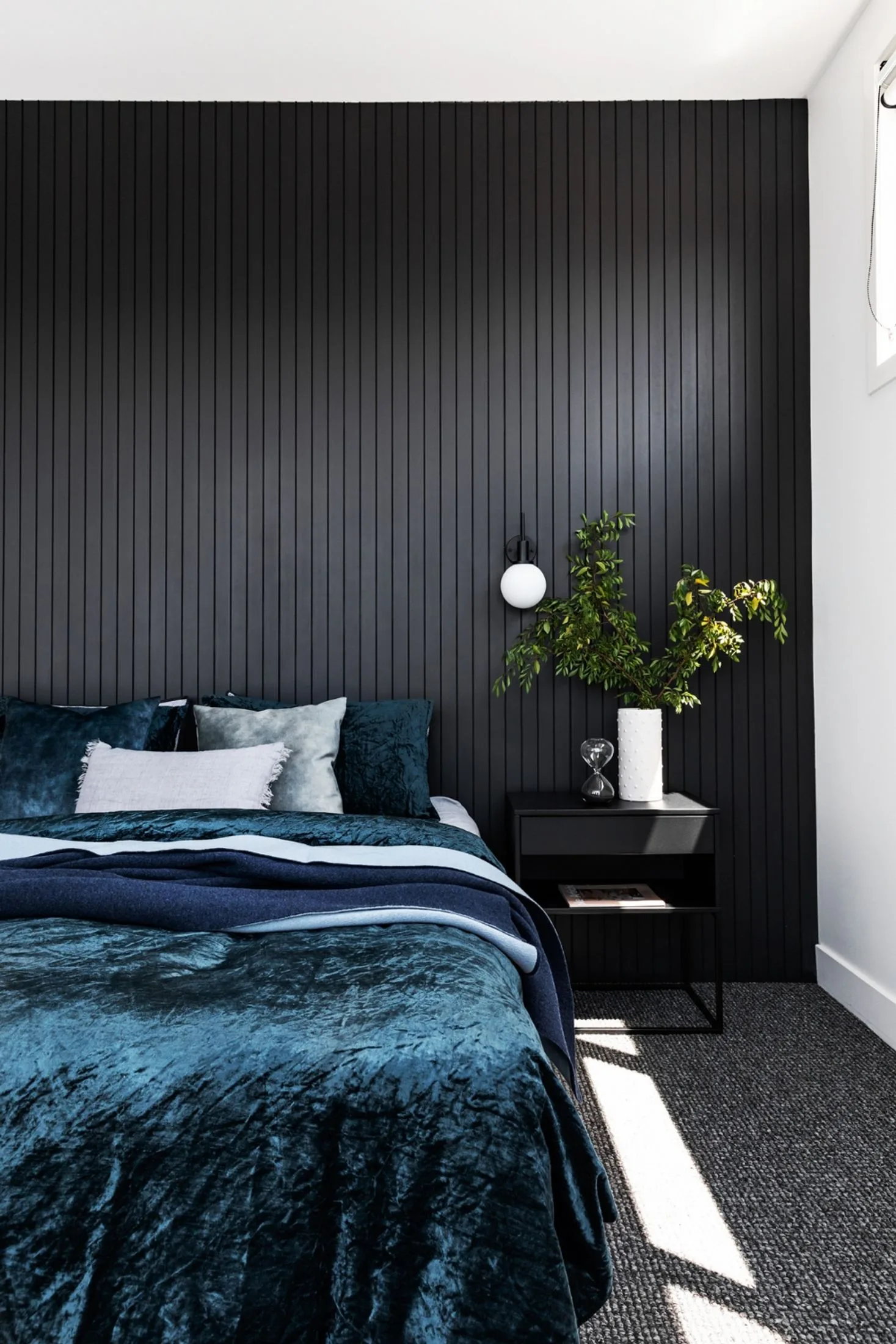 Dark and moody master bedroom with navy velvet bedspread and feature wall in Dulux Monument