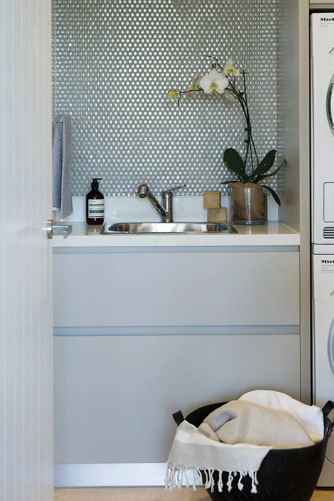 Tiny laundry with metallic penny round tiles splashback