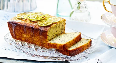 Lemon poppy seed loaf cake with slices on a crystal platter, garnished with candied lemon slices.