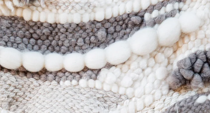 Close-up of a textured woven fabric in white and gray with assorted patterns and large yarn bubbles.