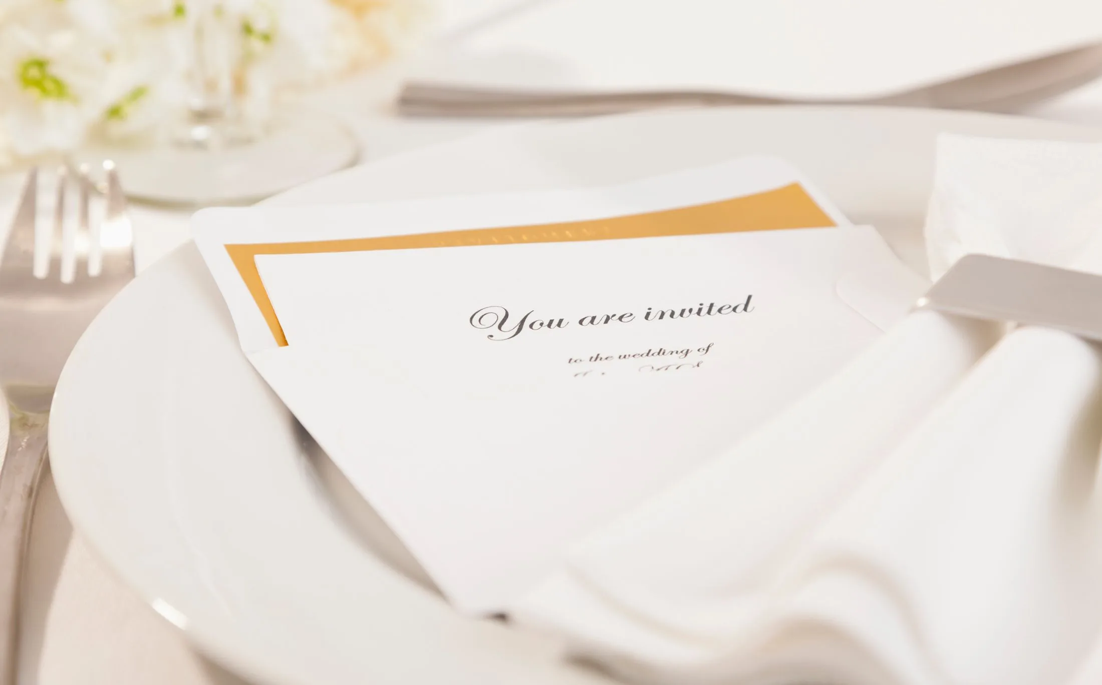 Wedding invitation card on a plate with fork, knife, and napkin; text reads "You are invited."