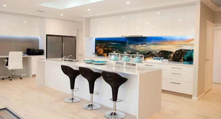 Modern kitchen with white cabinets, island with barstools, ocean-themed backsplash, and decorative jars.