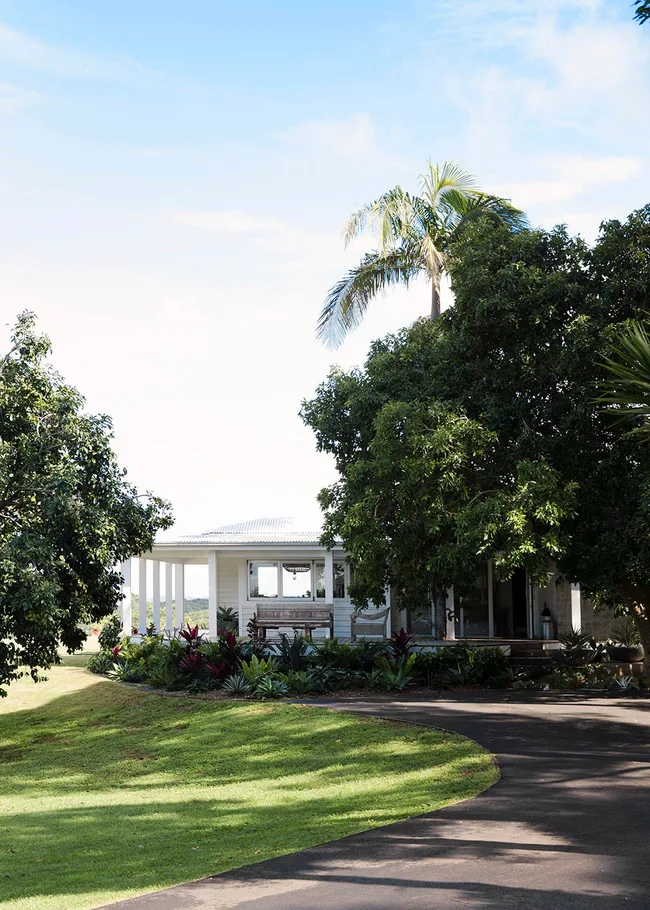 White house surrounded by lush greenery and trees under a clear blue sky.