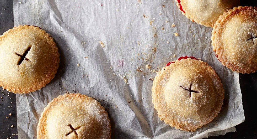 Golden brown hand pies with sugar topping and slits on parchment paper.