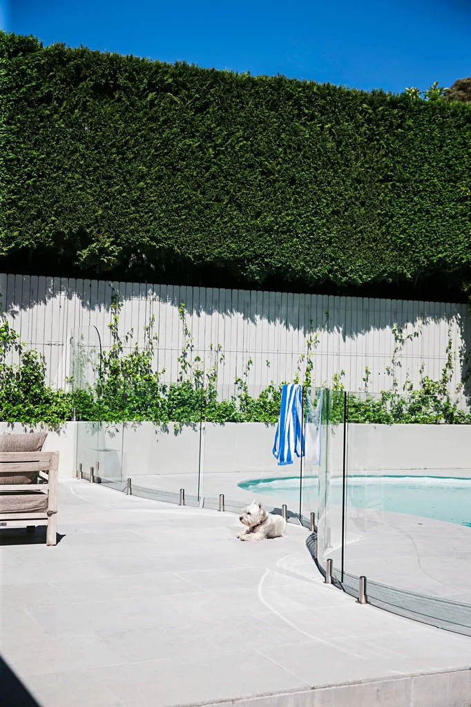 Oversized hedges stand guard around the resort-style pool in the home