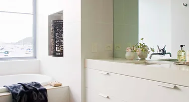 Modern bathroom with a white sink, flowers, faucet, and window view of sailboats on the water.