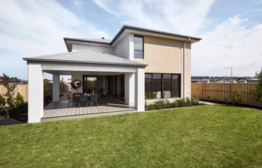 Modern two-story house with a spacious backyard, patio, and outdoor dining area under a covered deck.