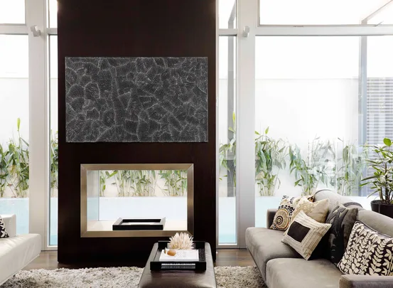 Modern living room with a dark accent wall, abstract art, fireplace, and light sofas adorned with patterned cushions.
