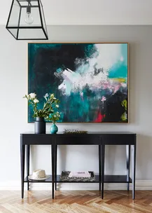 Elegant console table with floral decor and abstract painting on wall.
