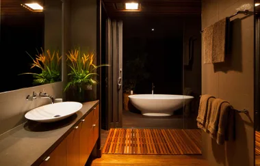 Elegant bathroom featuring a modern sink, vibrant plant, soft towels, and a freestanding bathtub by a glass door.