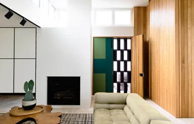 Stylish living room with wooden accents, a green entrance door, fireplace, and beige sofa.