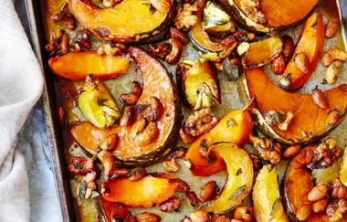 Roasted pumpkin slices with almonds, walnuts, and cashews on a baking tray.