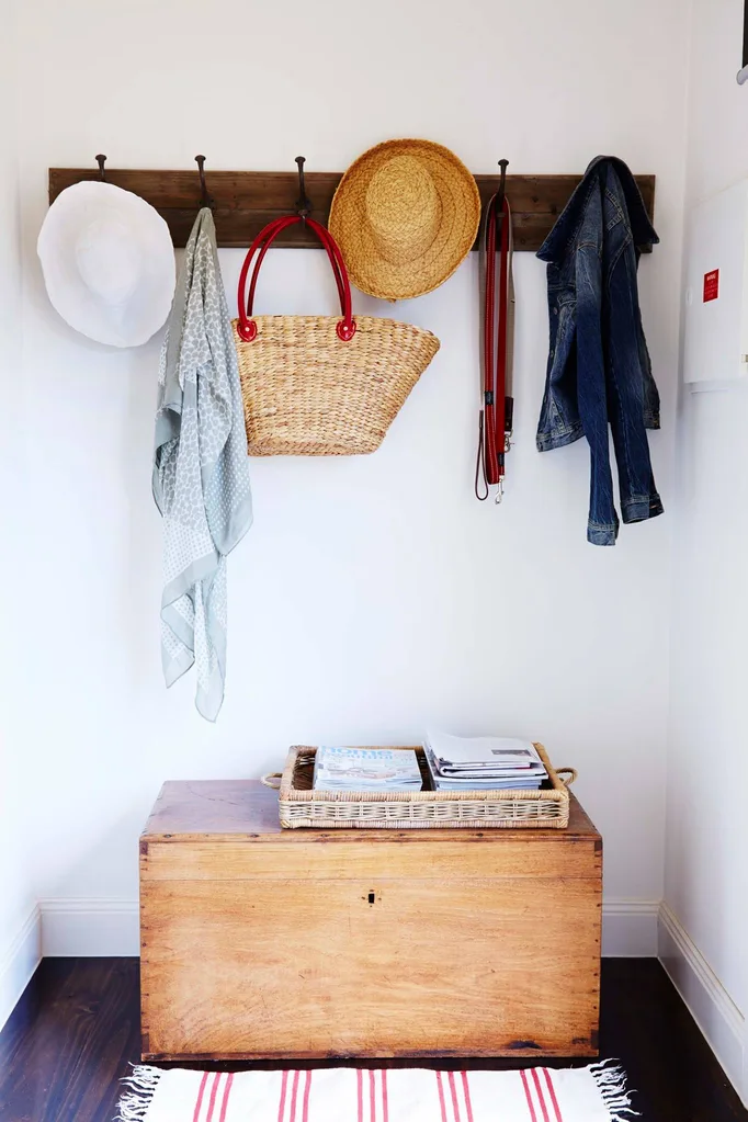 A timber storage chest for shoe storage beneath wall mounted hooks with hats and scarves