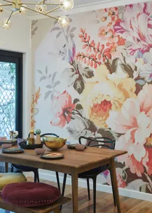 Dining area with a wooden table, floral wall mural, and modern lighting.