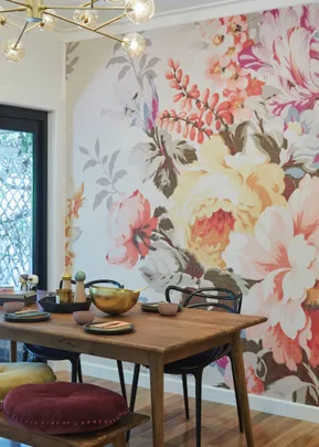 Dining area with a wooden table, floral wall mural, and modern lighting.