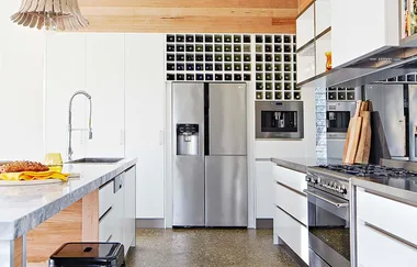 Modern kitchen with stainless steel appliances, wine rack, and marble countertop.