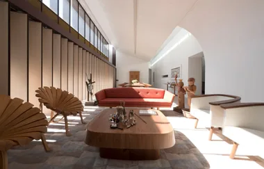 Modern living room with wooden furniture, a red couch, sculptures, and large windows casting light.