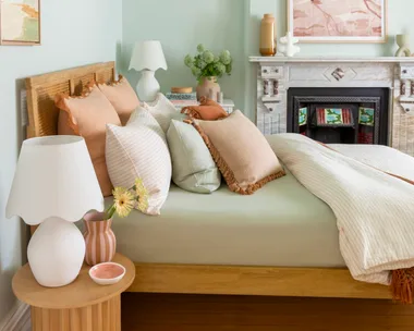 blue painted bedroom with sage green bed in the middle and neutral coloured cushions