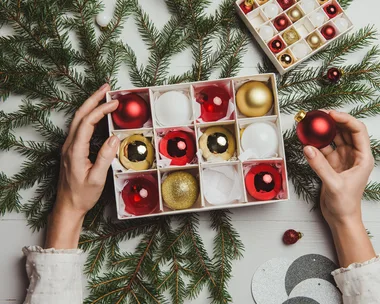 Hands placing Christmas baubles into a cardboard storage box