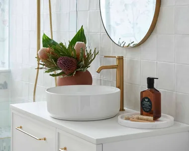 Renovated warm white modern bathroom with white vanity and basin and gold tapware