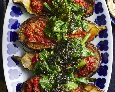 picture of four slices of eggplant cooked with miso sauce and asian greens on top. One blue plate with flowers around the edge
