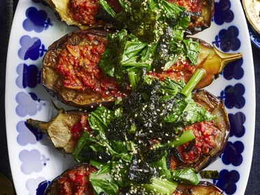 picture of four slices of eggplant cooked with miso sauce and asian greens on top. One blue plate with flowers around the edge