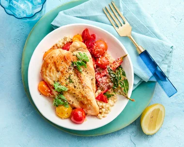 pan fried chicken in bowl with couscous vegetables against a blue background