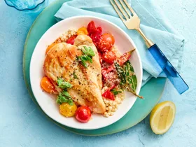 pan fried chicken in bowl with couscous vegetables against a blue background
