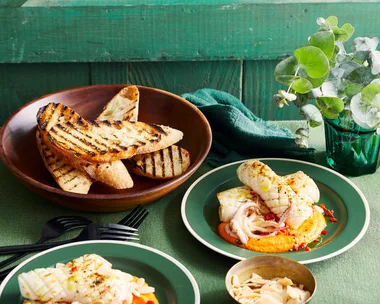 grilled squid with romesco orange sauce on the bottom, chargrilled bread slices in background