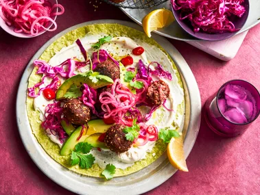 open wrap with purple pickled onion and beetroot on top of falafel