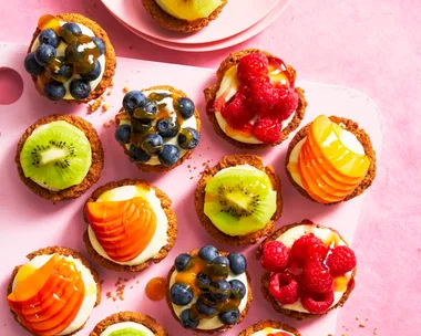 individual fruit tarts shot from birds eye view with blueberries, kiwi, peach and raspberries on them