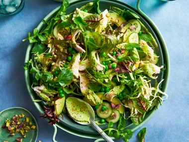 green salad with peas and salad with spoon sticking out and handle bowl