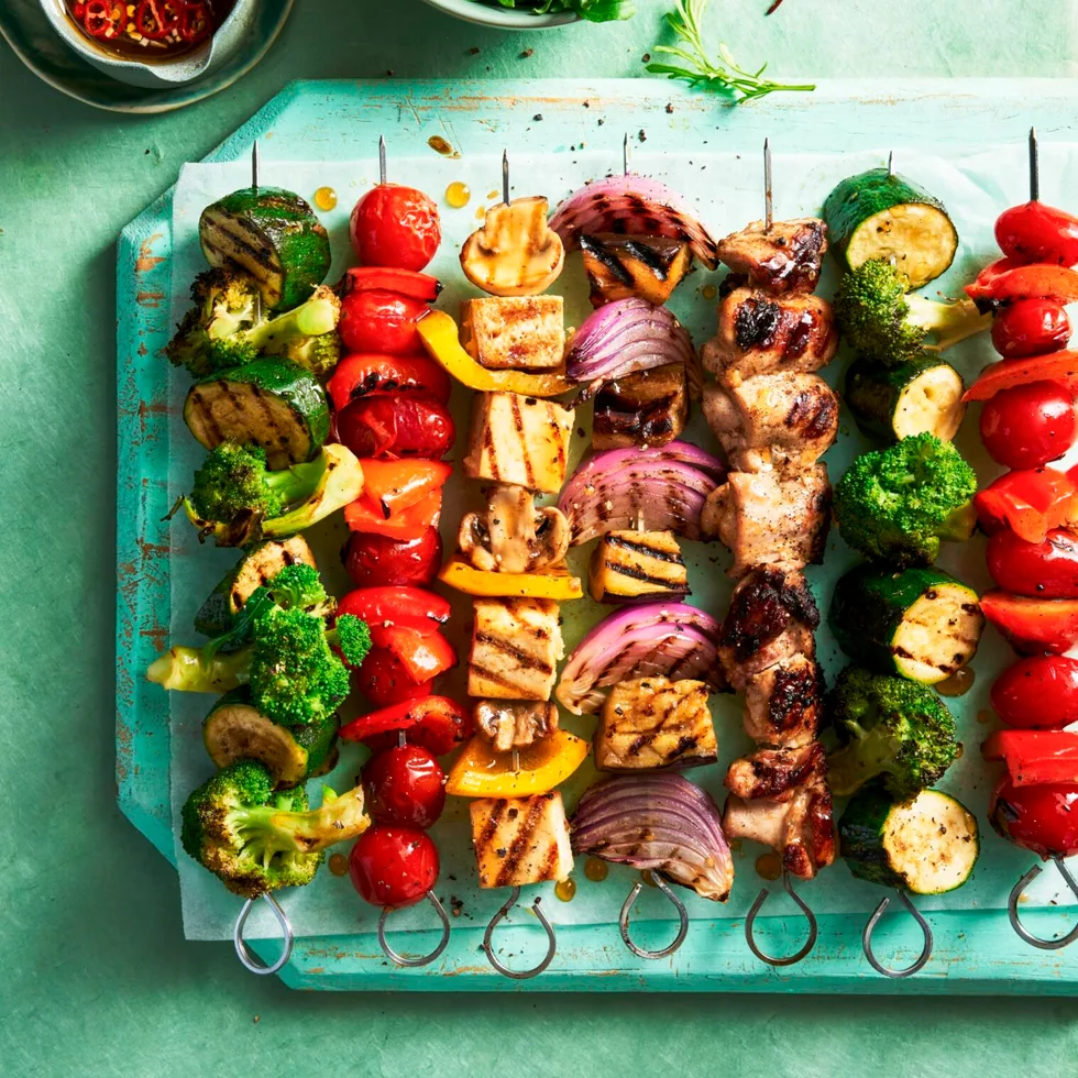 vegie skewers with tofu and meat on them in a line resembling rainbow colours