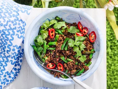 green beans with minced pork in a white bowl with grass background