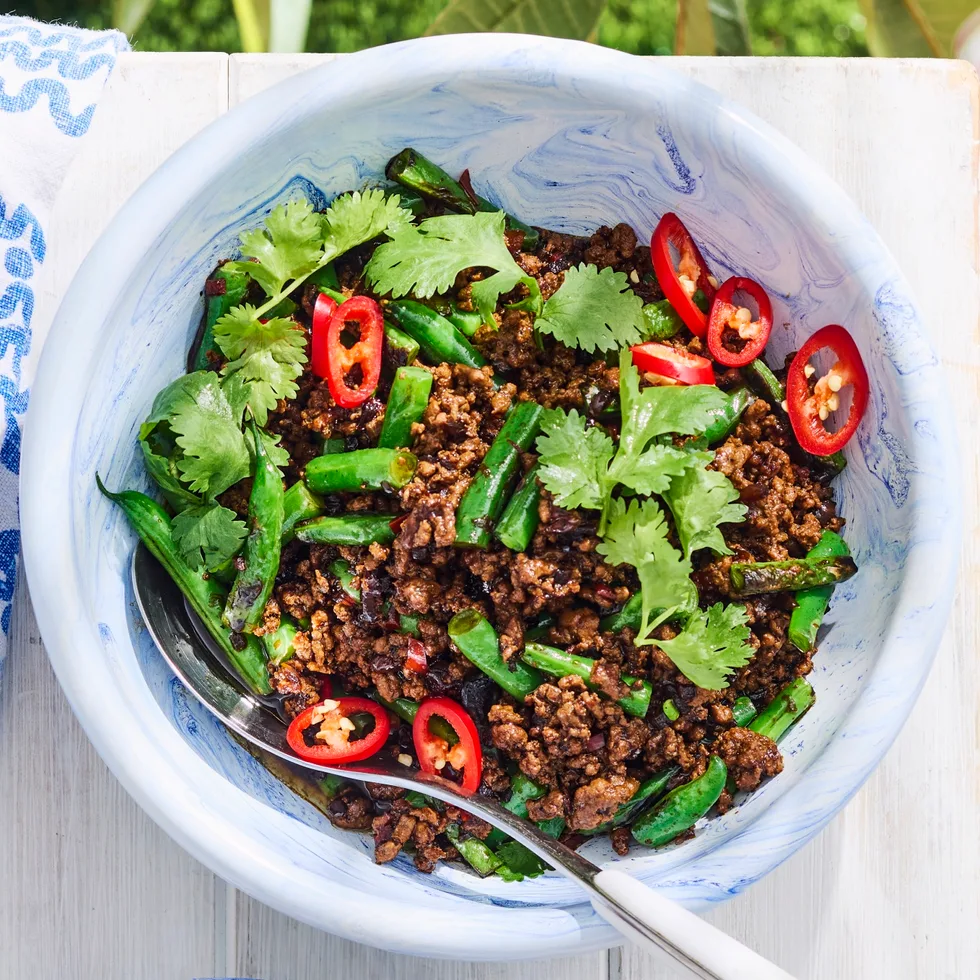 green beans with minced pork in a white bowl with grass background