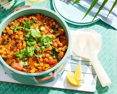 ratatouille in bowl with spoon on side and blue background