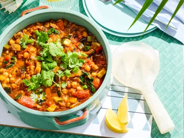 ratatouille in bowl with spoon on side and blue background