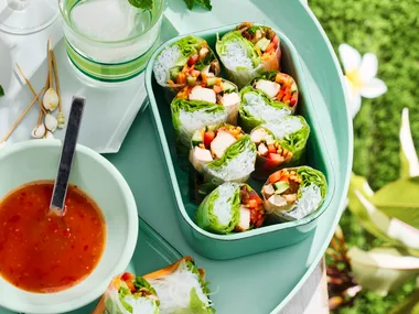 chicken teriyaki rolls in lunchbox with bowl of sauce next to it