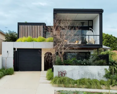 black square sustainable carbon neutral house with grass out the front and big concrete driveway
