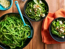 bright green pasta sauce with spaghetti in it in black bowls
