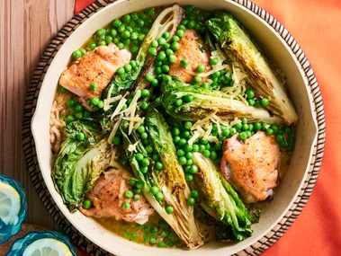 chicken peas bacon and charred lettuce in pan with sprinkle of herbs on top