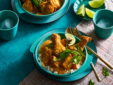 chicken curry in two bowls orangey colour with blue and teal colouring of bowls