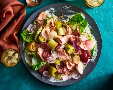 braised leeks poached trout salad in a black bowl on teal tablecloth