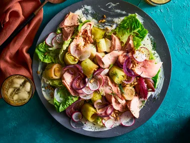 braised leeks poached trout salad in a black bowl on teal tablecloth