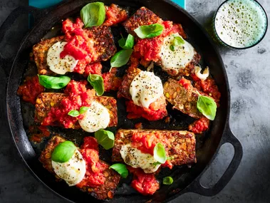 parmigiana meatloaf with basil on top in black casserole dish