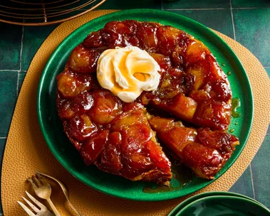 apple tarte tatin with dollop of double cream on top in green bowl
