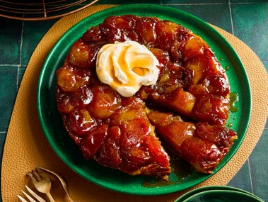 apple tarte tatin with dollop of double cream on top in green bowl